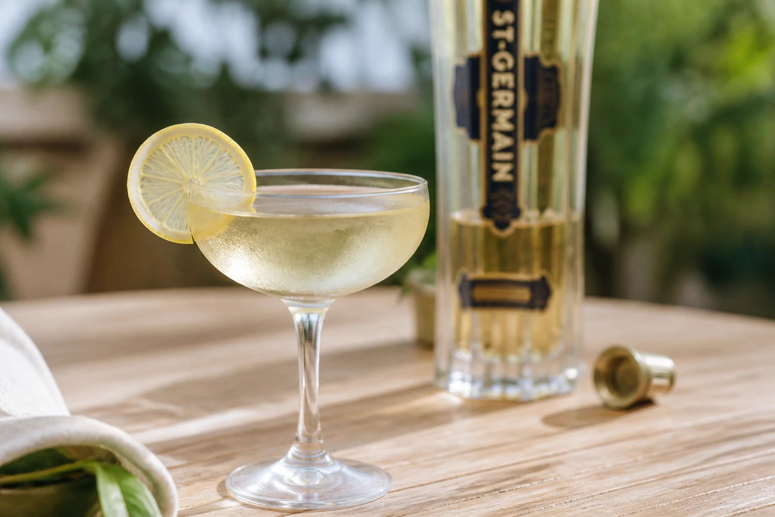 Cocktail Saint-Germain garni d'une rondelle de citron servi dans un verre givré sur une table en bois