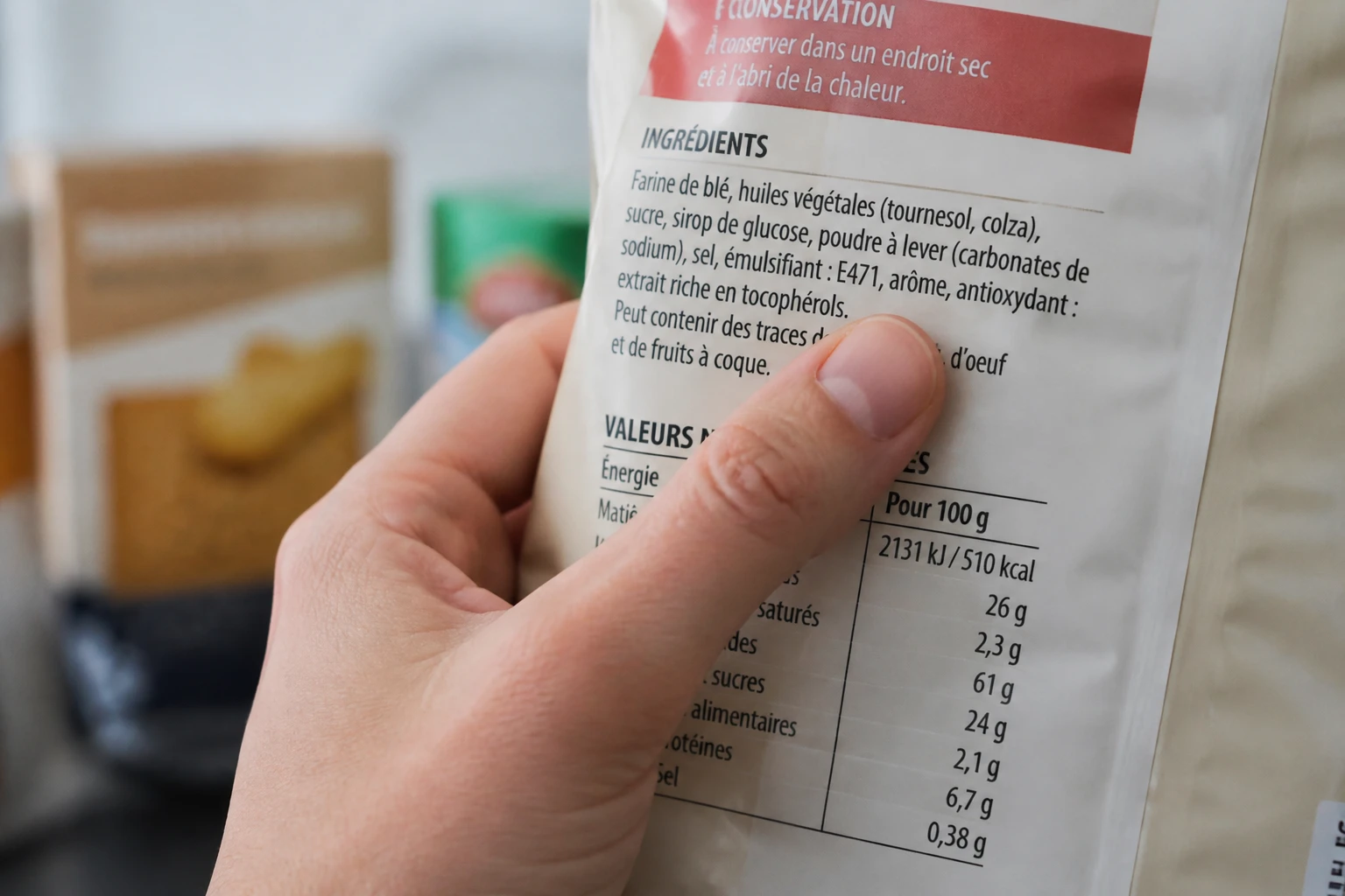 Main pointant du doigt la mention E471 sur une étiquette alimentaire